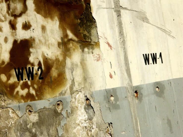 an old white wall with peeling paint and writing