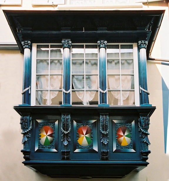 an old fashioned window with decorative elements with umbrellas hanging from it