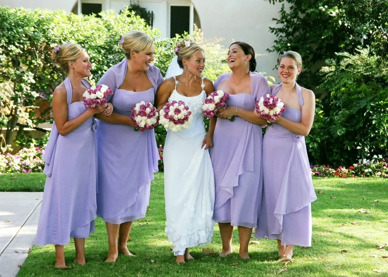 several beautiful bridesmaids pose in front of some bushes