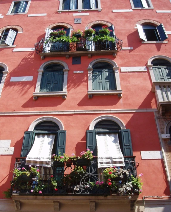 a building has many windows, lots of flowers and shutters