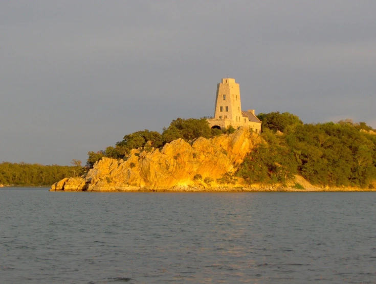 a tower with a large opening in it sits on a small island