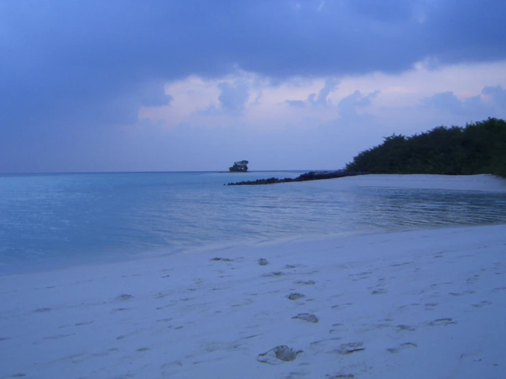 a person walking along a white sandy beach near the ocean