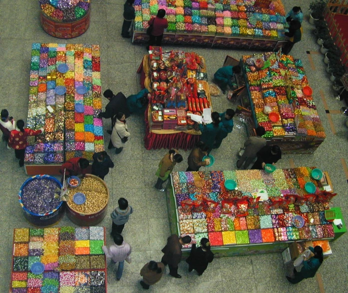 several people at tables and carts filled with colorful items