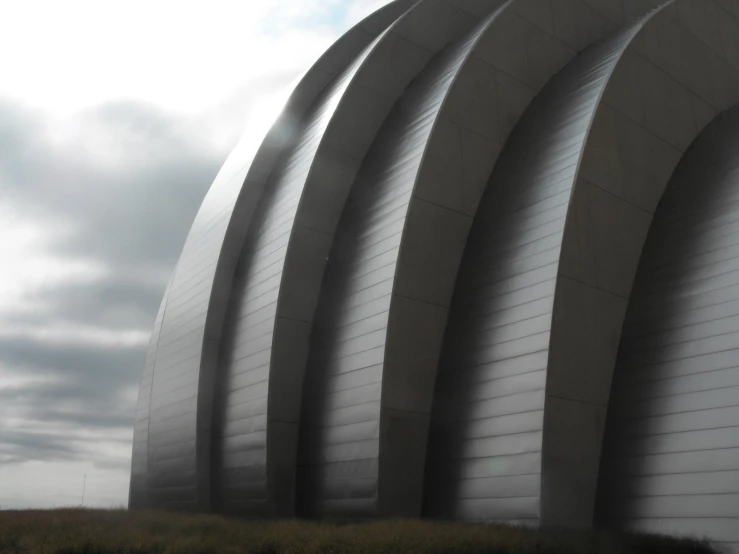 a very big curved building with a blue sky in the background