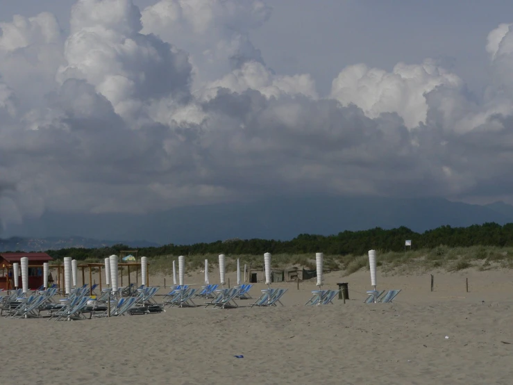 many lawn chairs sitting on top of a sandy beach