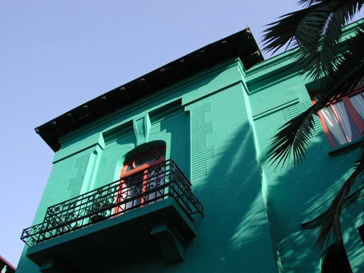 a person standing at a balcony near a palm tree