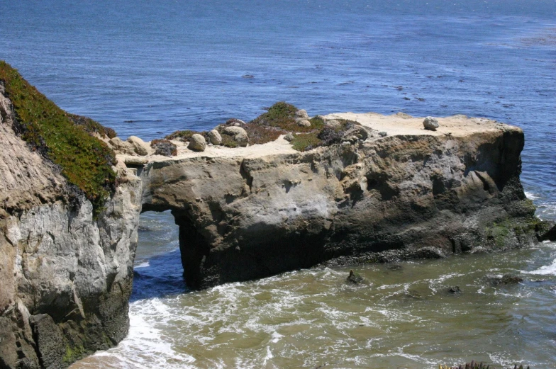 a stone bridge between two rocky cliffs, by the ocean