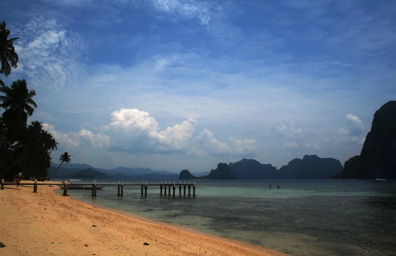 boats on the beach at an island with a cloudy sky