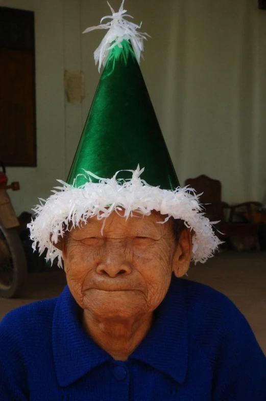 an old asian woman with green and white hats