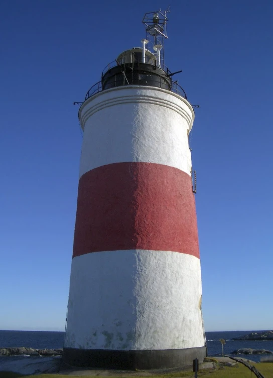 the large white and red lighthouse is near a body of water