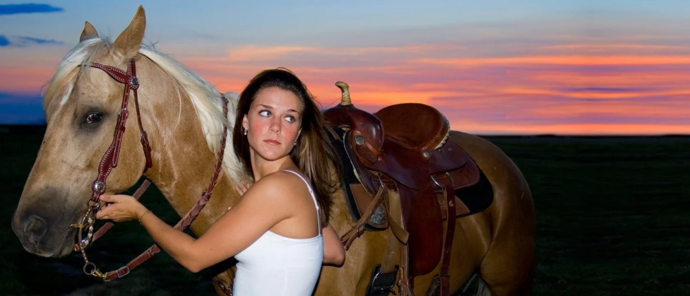 a beautiful woman posing next to a horse in a pasture