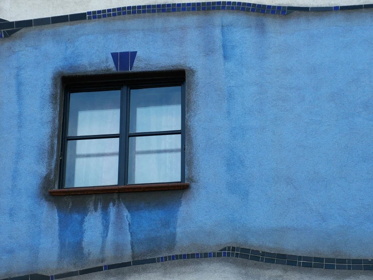 a blue building with an open window and tile back splash