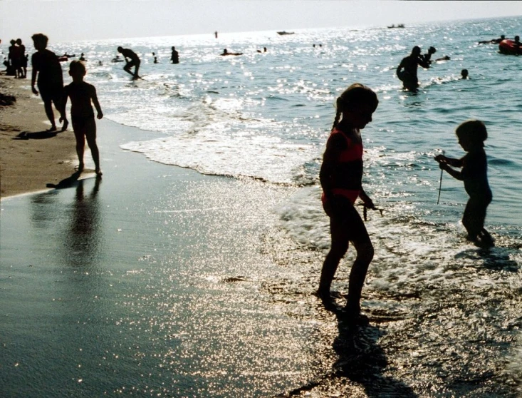 the children are walking along the shore in the water