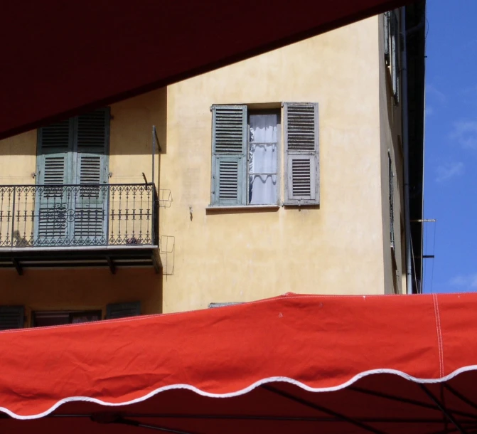 an umbrella stands in front of the balcony at a yellow building