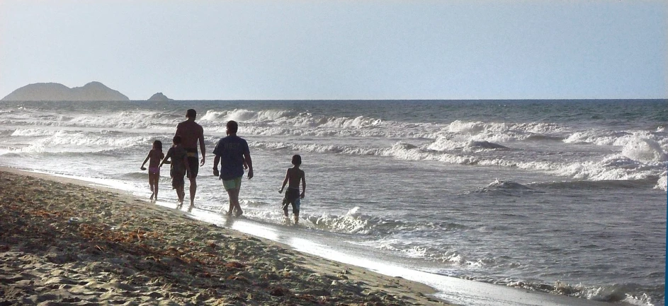 three people are walking on a beach with their child