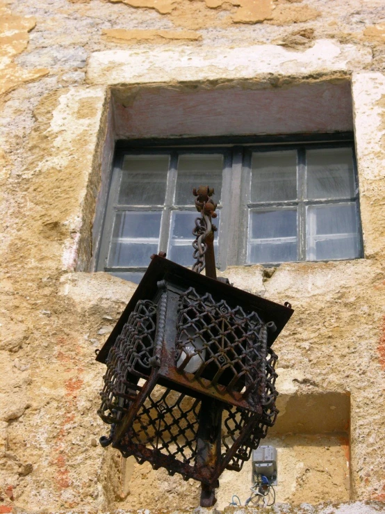 an iron grate hanging from a brick wall next to a window