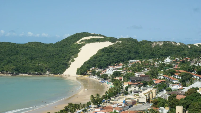 a beach and forested hills overlooks a town