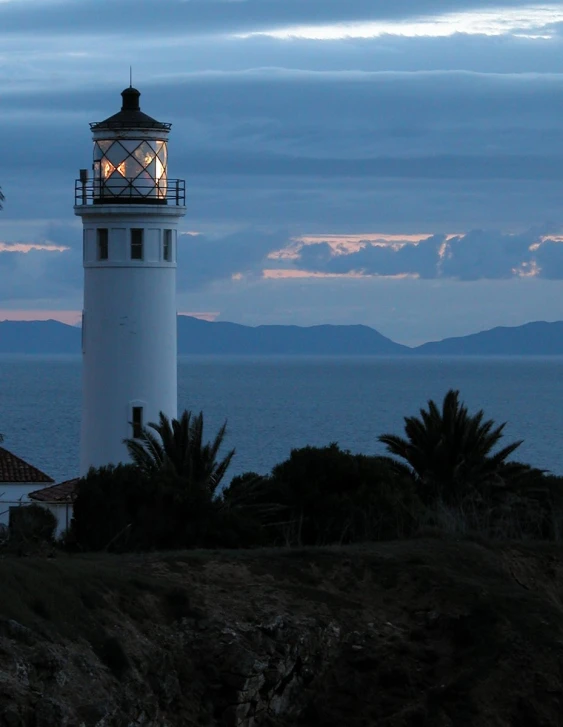 a lighthouse is lit up with lights in front of the ocean
