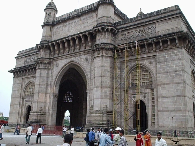 people are walking around a large building with lots of stone