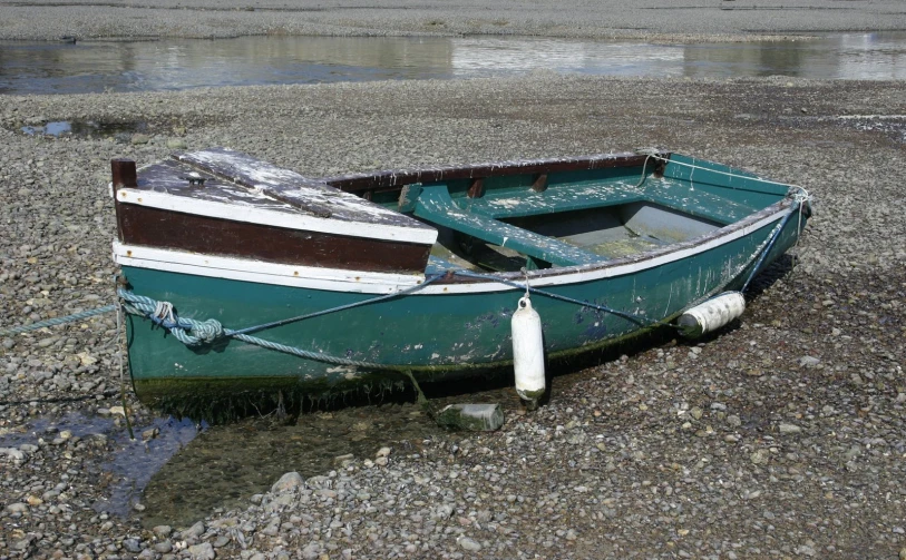 a blue and white small boat sitting on the beach