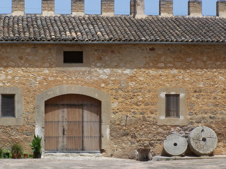 the old building with a wood door and windows has stone columns, some with round cut outs