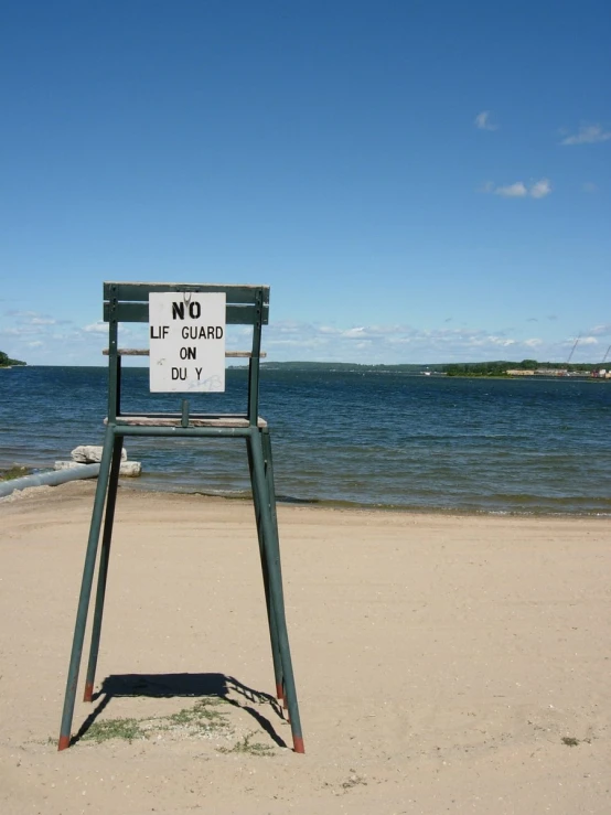 the chair is placed next to a sign on the beach