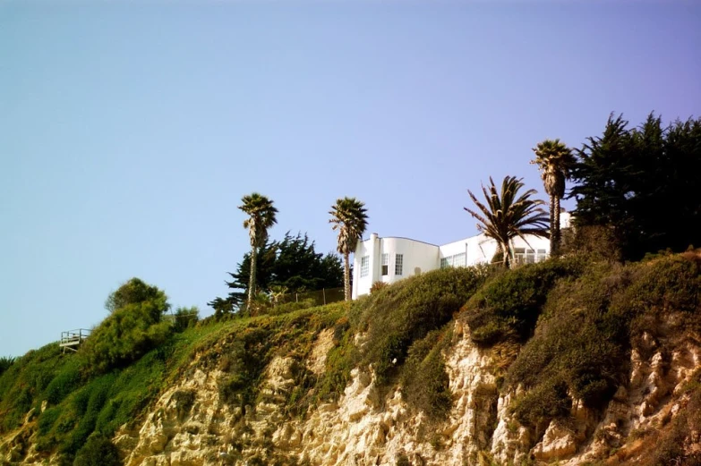 a white building is sitting on the side of the hill