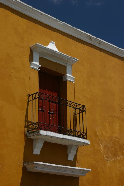 a bright orange building with a balcony and red door