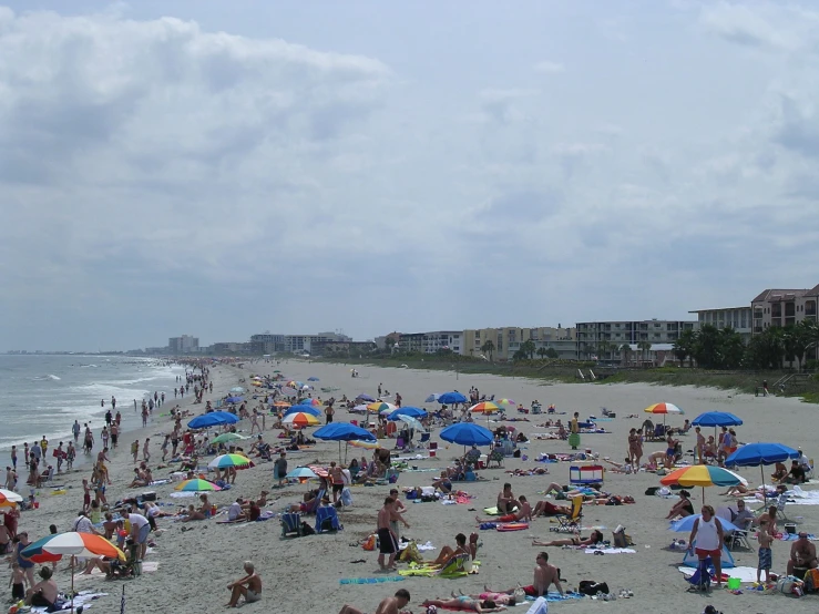 a crowded beach with many people enjoying the sun and water