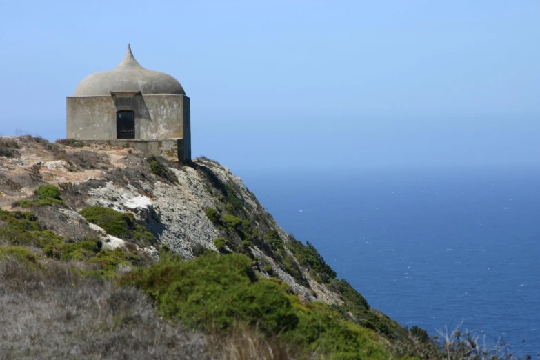 a small gray building on the side of a cliff