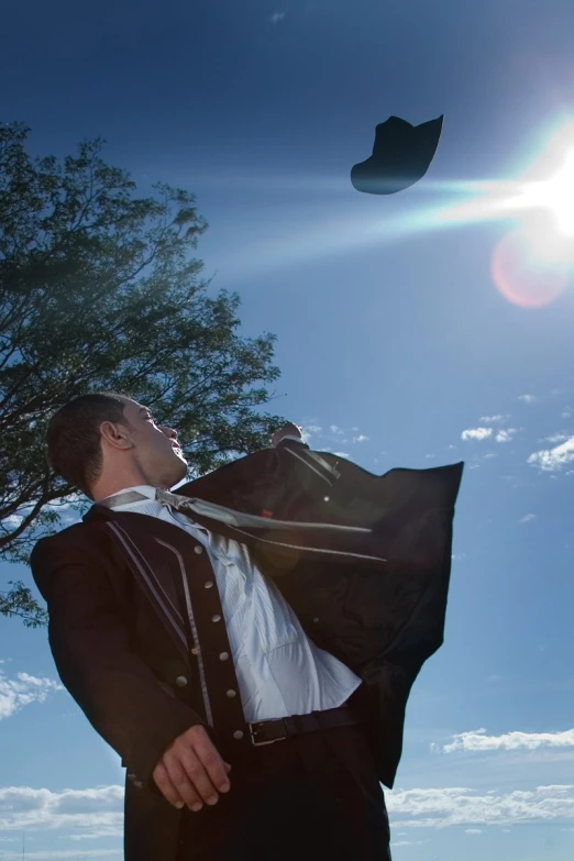 a man dressed in black and a tie is flying a kite