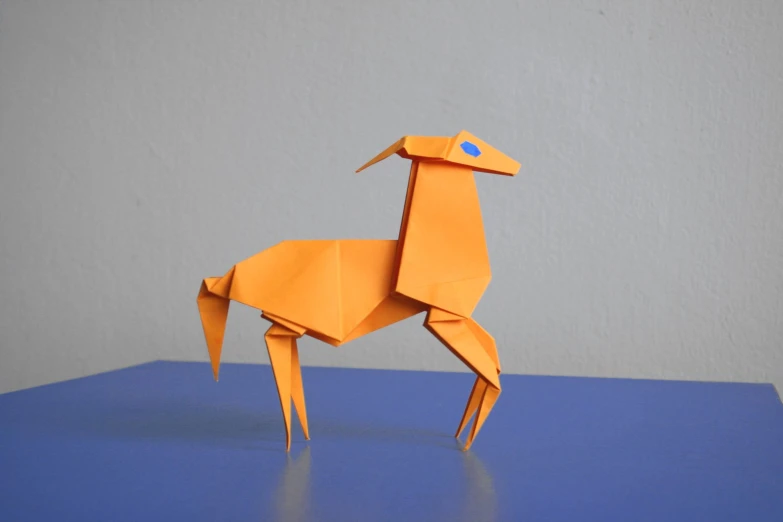 an origami giraffe standing upright on a blue surface