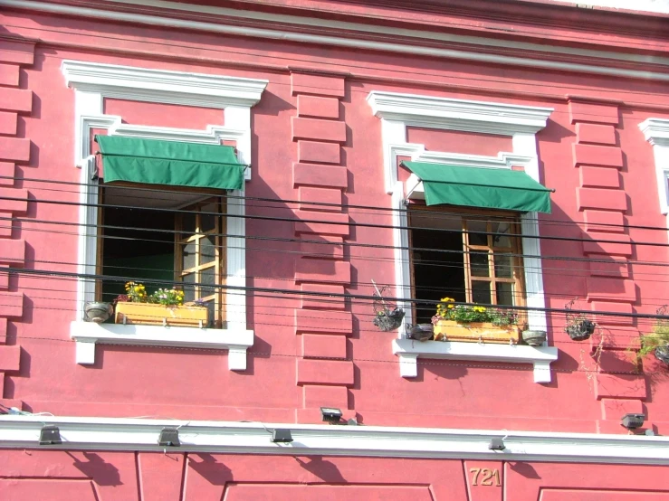 a pink building with some green shutters on the side