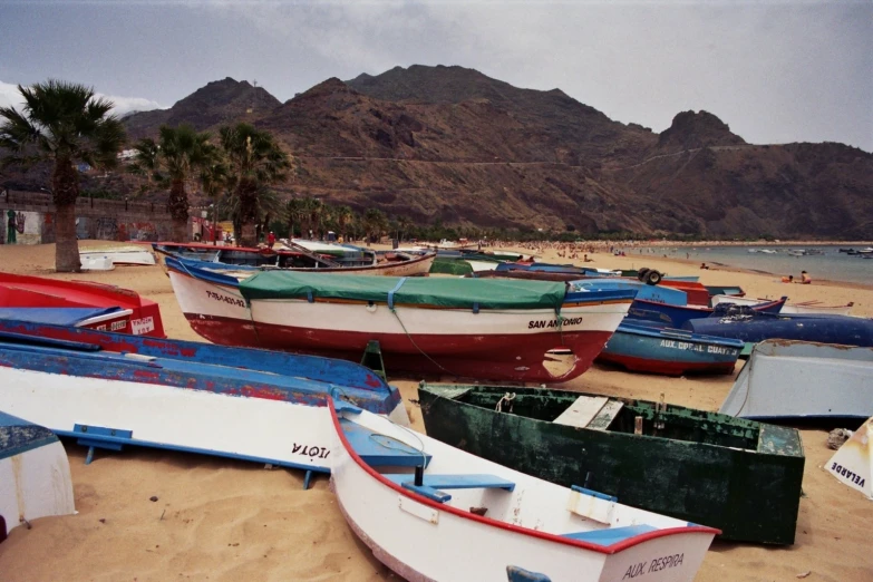 several boats are on the beach near some mountains