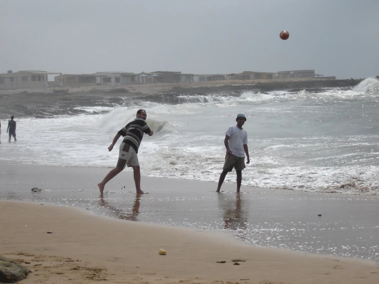 two men are playing at the edge of the ocean