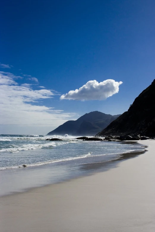 the beach is sandy, and has gentle waves crashing against it