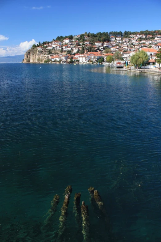 the water is crystal clear and blue as it looks down at town on the hill side