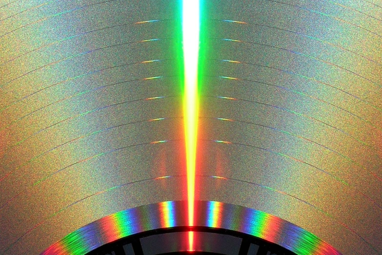 a black circular with a rainbow and a pink light