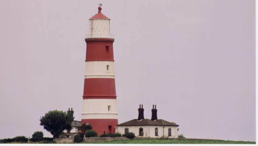 a white and red light house sitting on top of a hill