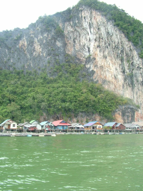 boats are in the water near houses on a cliff