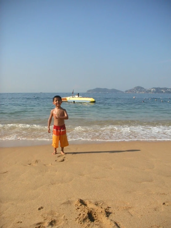 a little boy walking on the beach toward the water