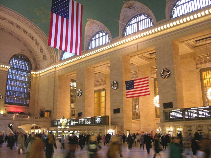 the interior of a grand central station at night with lights on and large flags on the ceiling