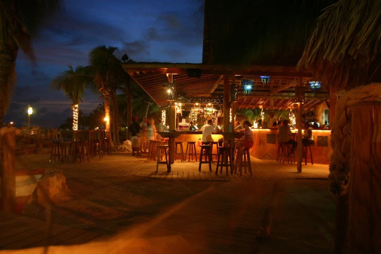 a restaurant lit up with palm trees on the beach