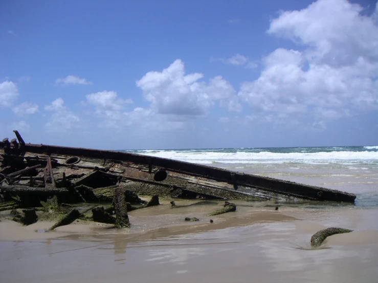 a rusted wooden ship on the shore of an ocean