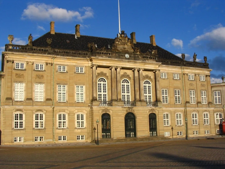 a tan building has white windows and a black roof