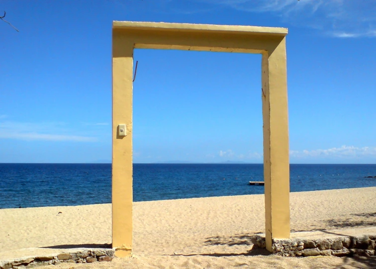 an archway made of yellow material next to a beach