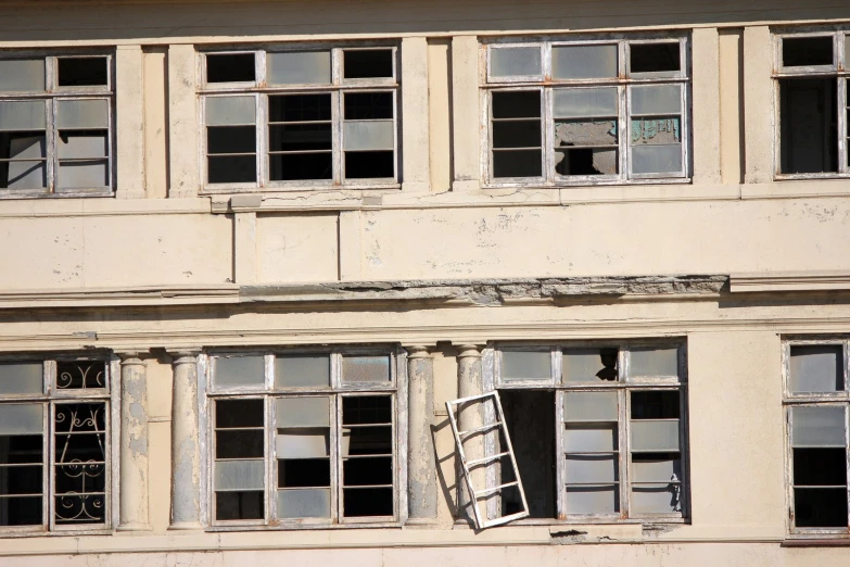 two windows and a broken ladder on a building