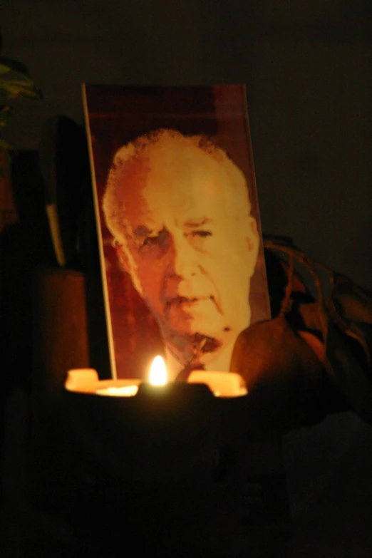 a person holding a candle with the face of nelson on it