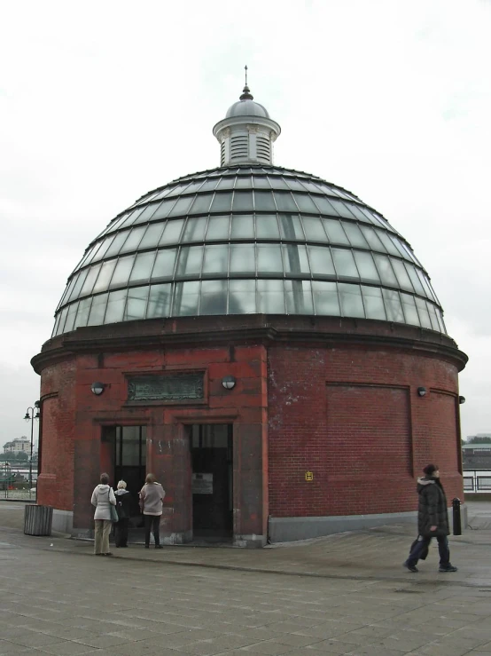 people walking outside a building with a very large domed roof