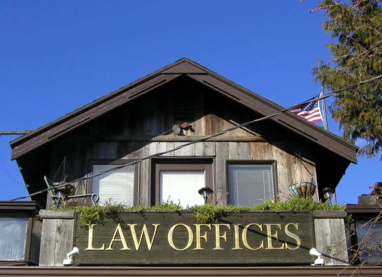 a wooden sign for a law office with two american flags on the top